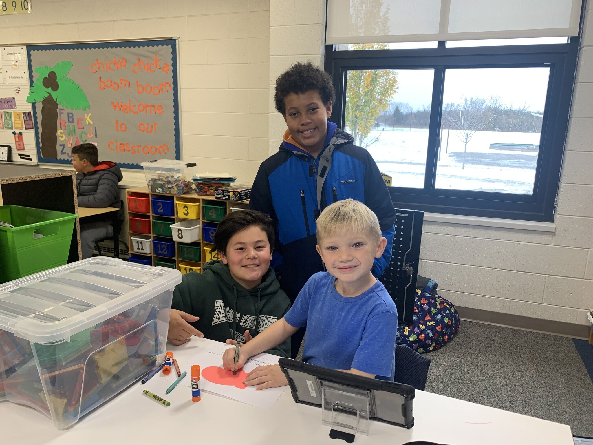 Two middle school students work with a kindergarten student on a coloring page.